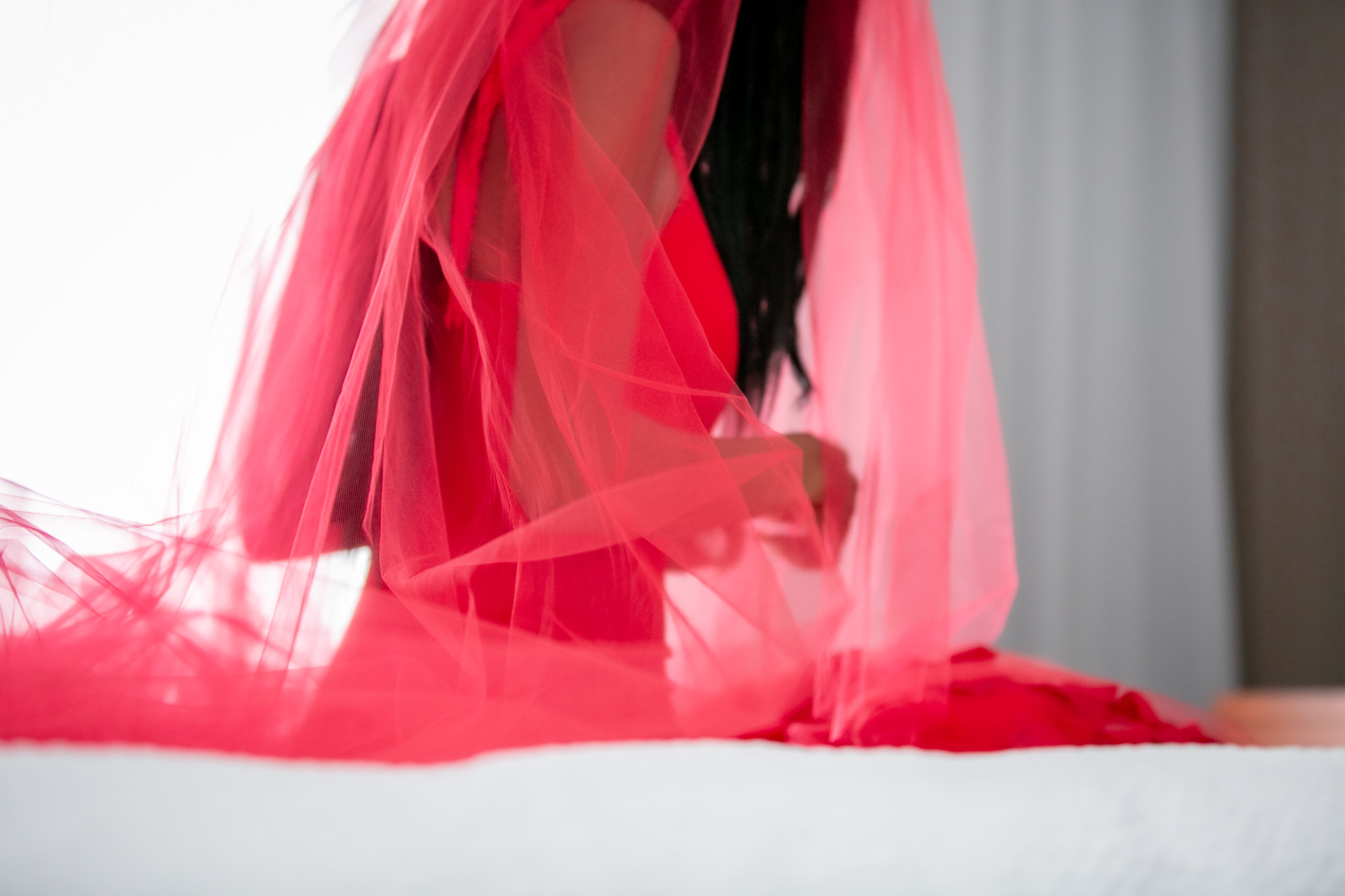 bride sitting in hotel room before her wedding in a red wedding dress