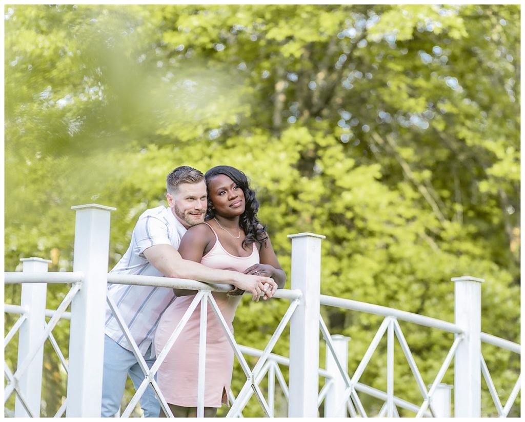 beautiful couple looking out on a bridge at their engagement photos session at sayen house and gardens